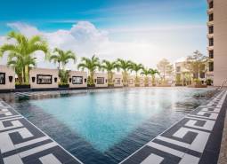A pool with palm trees under construction in an apartment complex in Pattaya under the blue sky.