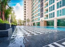 The construction of apartments in Pattaya includes a swimming pool, a high-rise building, and green plants.