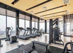 A gym with a view, equipped with treadmills and exercise machines. Apartment construction.