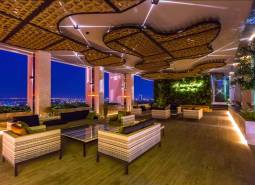 Luxury apartment space with a view of the city's evening lights, a green wall, and comfortable seating.