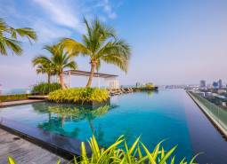 Infinity pool and palm trees on the rooftop with a view of the city skyline in Pattaya, apartment construction.