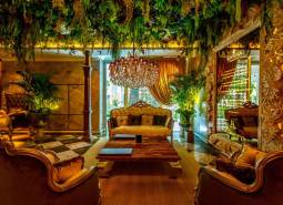 Luxurious living room with a chandelier, plants, and golden curtains as part of apartment construction.