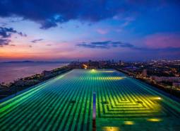 A view of the rooftop pool overlooking the evening skyline of Pattaya.