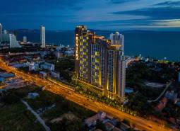 Construction of apartments in the city of Pattaya by the sea, illuminated skyscrapers and city skyline.