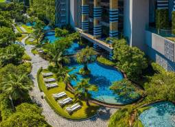 A swimming pool surrounded by greenery and walkways in a residential development in Pattaya.