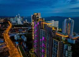 Night panorama of Pattaya with apartment construction by the coast, illuminated high-rise buildings.