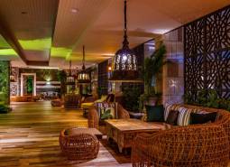 Interior of residential building with comfortable rattan furniture and decorative lighting.