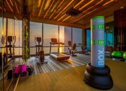 A fitness center with a view of the sunset through large windows, apartment construction.