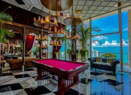 Luxury interior with a pool table, large windows, and an ocean view. Apartment construction.