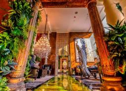 Luxurious interior with a chandelier, decorative columns, and greenery in the construction of apartments.