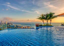 Apartment construction in Pattaya with sea views, a swimming pool, and palm trees on the terrace.