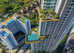 The construction of apartments in Pattaya features a high-rise building with a pool and a rooftop garden.