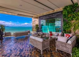 Apartment construction with terrace and sea view in Pattaya, comfortable seating and greenery.