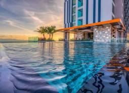 Infinity pool under construction in an apartment building in Pattaya, at sunset with palm trees in the background.