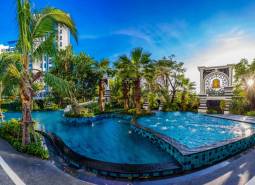 The construction of apartments in Pattaya includes a pool with greenery and palm trees.