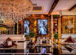 Luxurious interior with a crystal chandelier, golden decor, and artistic photographs on the wall.
