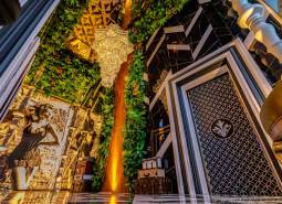 Luxurious interior with a large chandelier, mirrored wall, and green decorations in apartment construction.