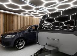 A car and a caravan inside commercial premises with lighting and wooden walls.
