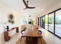 Dining room in a family house with a wooden table and a view of the yard through glass doors.
