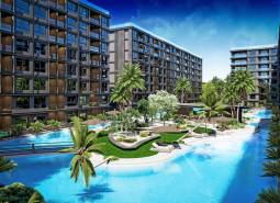 Apartment construction in Pattaya with green areas and a swimming pool among modern buildings.