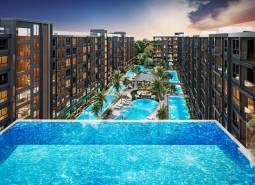Apartment construction in Pattaya with large pools and palm trees between the buildings.