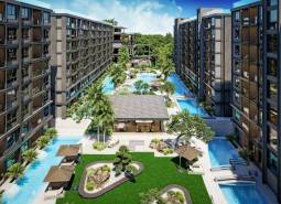 Apartment construction in Pattaya with a swimming pool, palm trees, and relaxation areas in the garden.