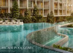 A pool with cascades during the construction of apartments in Phuket with loungers and greenery.