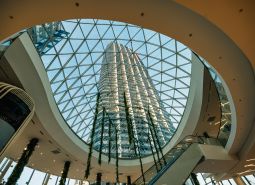 A spacious atrium with a glass roof and a tall building in the background.