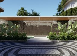 The exterior of an apartment building under construction in Phuket, with foliage and a decorative wall under a canopy.