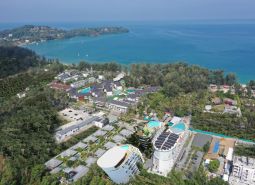 Aerial view of apartment construction near the coast of Phuket with lush greenery.