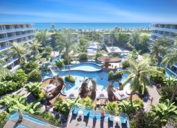 Apartment construction in Phuket with a swimming pool, palm trees, and a sea view.