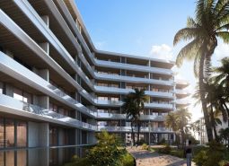 Apartment construction in Phuket with terraced balconies among palm trees and blue skies.