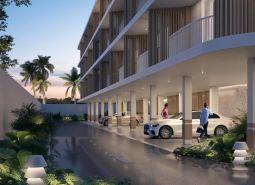 Apartment construction in Surat Thani: parking under a modern building surrounded by tropical greenery.
