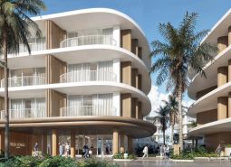 Construction of apartments in Surat Thani with curved balconies and palm trees in the background.