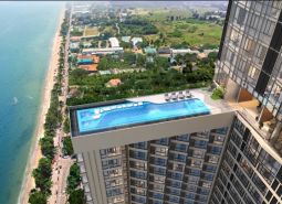 Apartments construction in Pattaya with a swimming pool and a view of the sea and beach.