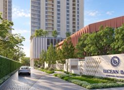 Apartment construction in Pattaya with a high-rise building, greenery, and a car on the driveway.