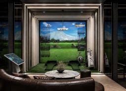 Indoor golf simulator with a comfortable sofa and electronic controls, Apartment construction.