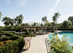 Garden and pool in the apartment complex in Phuket, lined with palm trees and greenery.