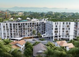 Construction of apartments in Phuket with a view of the sea and surrounding palm trees.