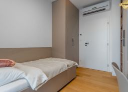 Single room with a bed, built-in wardrobe, and wood-patterned flooring.