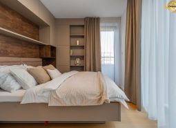 Bright bedroom with beige curtains, shelves, and a wooden decor floor in the apartment construction project.