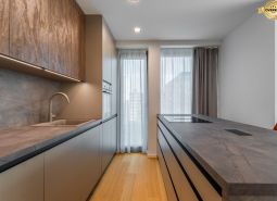 Modern kitchen with wood-patterned flooring and light curtains, Apartment construction.