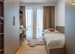 A minimalist room with a bed, a desk, and a wooden floor decor. Apartment construction.
