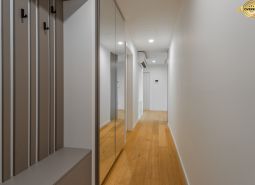 A hallway with a wooden decor floor and a mirrored wardrobe, Apartment construction.