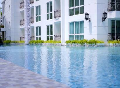 Apartment construction in Pattaya with landscape architecture and a pool in the background of the buildings.