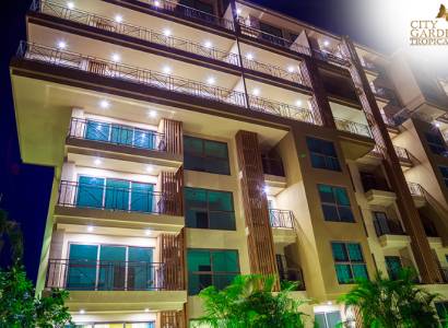 Apartment construction in Pattaya with an illuminated facade and numerous balconies at night.
