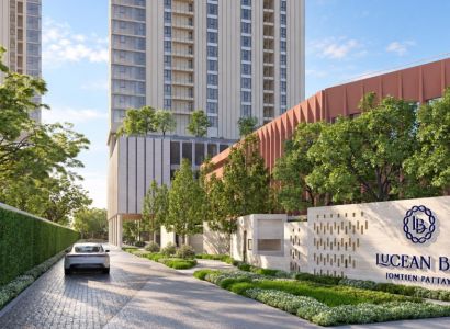 Apartment construction in Pattaya with a high-rise building, greenery, and a car on the driveway.