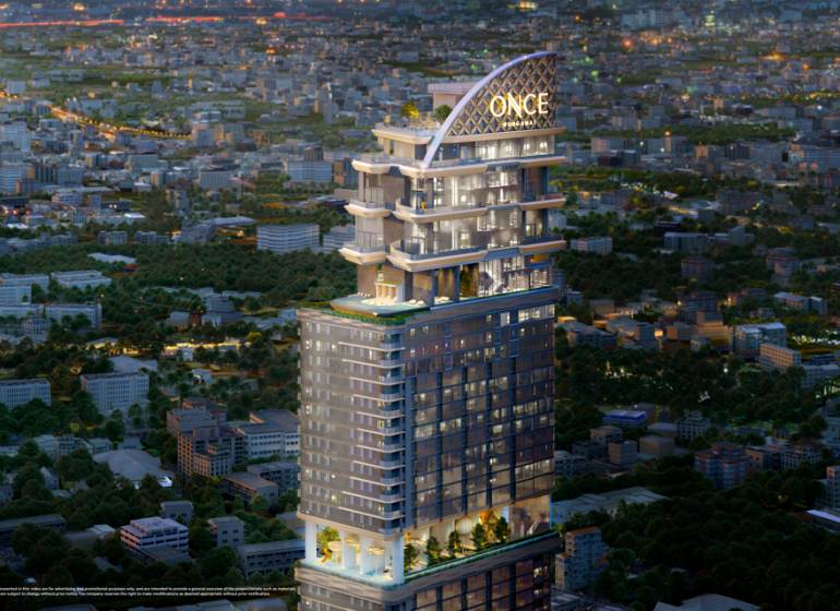 Apartment construction in Chon Buri 20150 with a bright skyscraper during the evening.