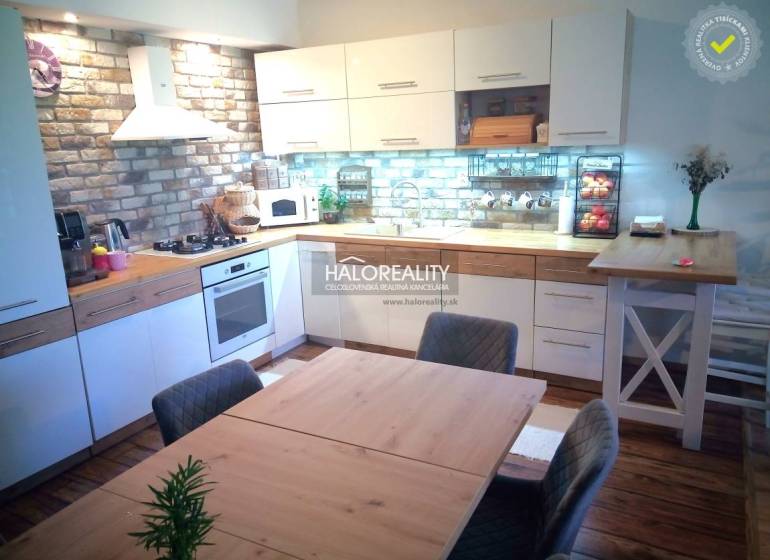 The kitchen in the 3-room apartment combines brick tiles, white cabinets, and wooden elements.