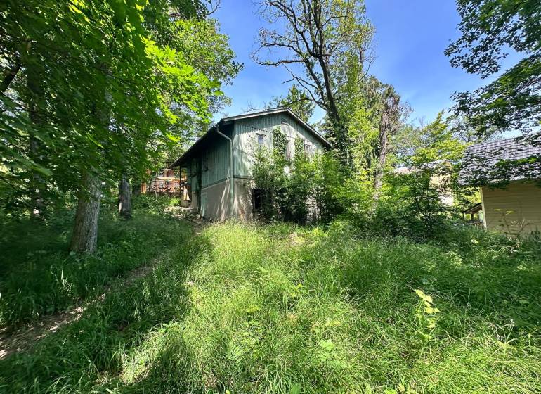 A cottage in a natural setting on Harmónia Street in Modra, surrounded by greenery and trees.
